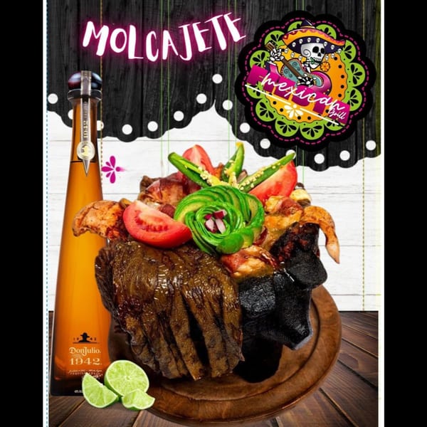 A Molcajete dish with meat, vegetables, and avocado, next to a bottle of Don Julio 1942 tequila.